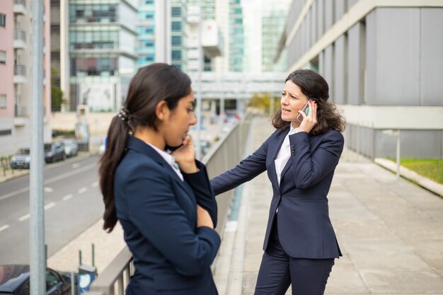 Empresaria seria hablando por teléfono inteligente