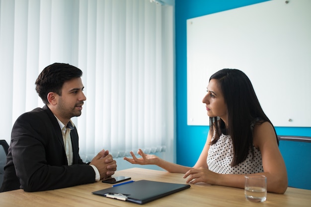 Empresaria seria y hombre de negocios hablando en sala de juntas