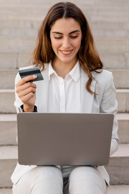 Empresaria sonriente de compras en línea con computadora portátil y tarjeta de crédito