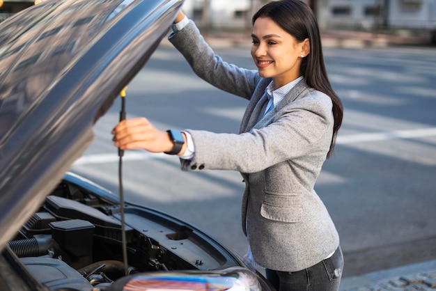 Empresaria sonriente levantando el capó del coche