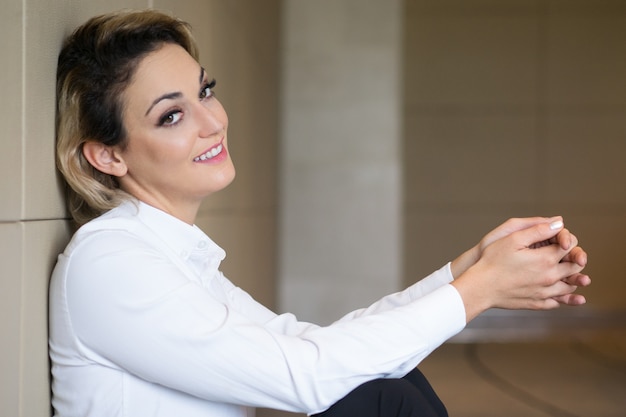 Foto gratuita empresaria sonriente de mediana edad sentado en el piso