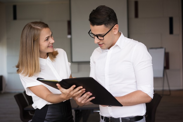 Empresaria sonriente que muestra la carpeta con el documento al hombre de negocios.