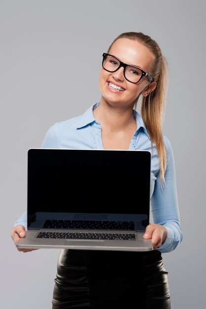 Empresaria sonriente que muestra la pantalla del portátil