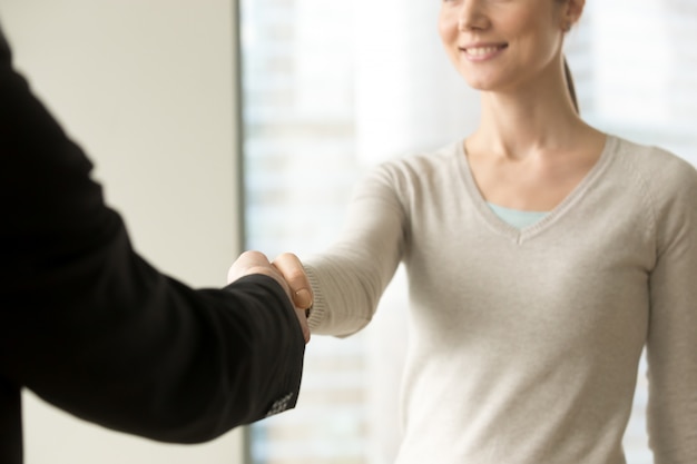 Empresaria sonriente que sacude la mano del hombre de negocios en oficina