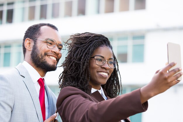 Empresaria sonriente que sostiene smartphone en brazo extendido