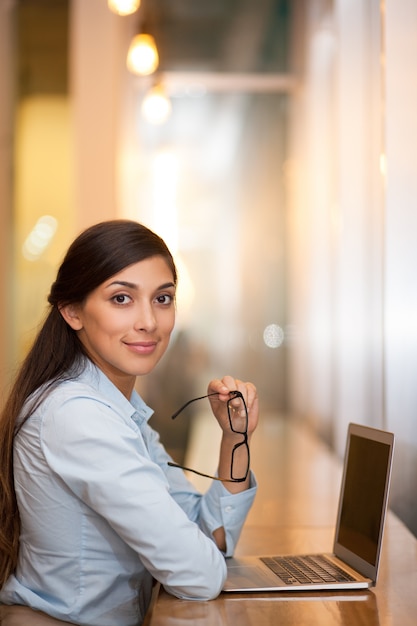 Empresaria sonriente que trabaja en la computadora portátil en el café