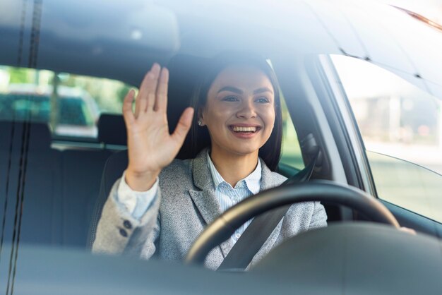 Empresaria sonriente saludando desde su coche