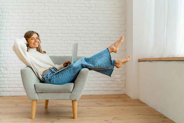 Foto gratuita empresaria sonriente sentado en el sofá en casa trabajando en equipo portátil