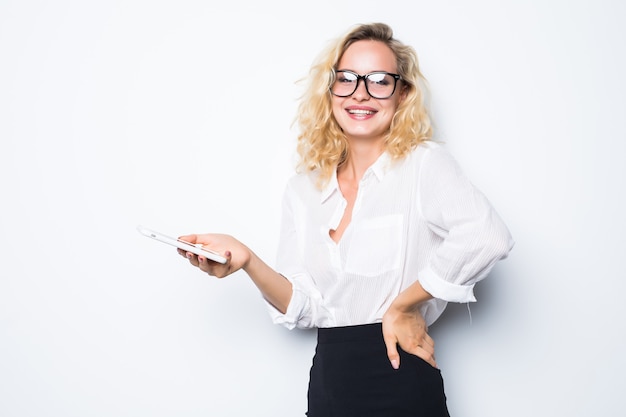 Empresaria sonriente con smartphone sobre pared gris. Vistiendo con camisa azul y gafas.