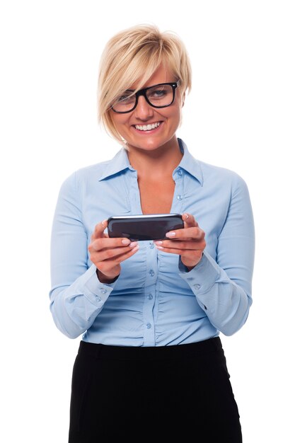 Empresaria sonriente sosteniendo teléfono inteligente y mensajería de texto