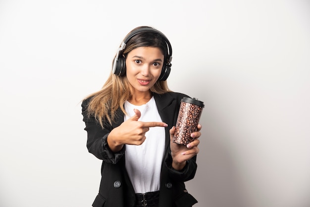 Empresaria sonriente con taza y auriculares.