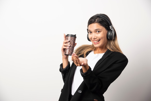 Empresaria sonriente con taza y auriculares.