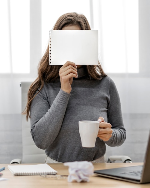 La empresaria sosteniendo un bloc de notas en blanco en su rostro