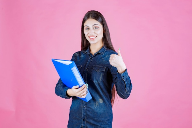 La empresaria sosteniendo una carpeta azul y haciendo buena señal