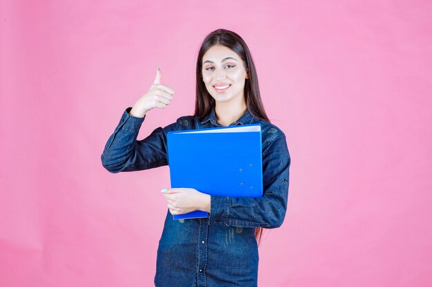 La empresaria sosteniendo una carpeta azul y haciendo buena señal