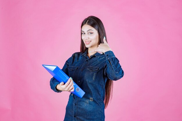 La empresaria sosteniendo una carpeta azul y haciendo buena señal