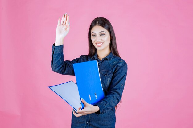 La empresaria sosteniendo una carpeta azul y saludando a alguien con un apretón de manos