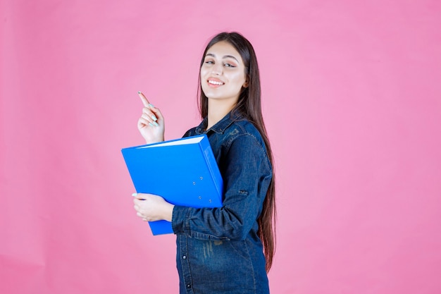 La empresaria sosteniendo una carpeta de informe azul y apuntando hacia arriba