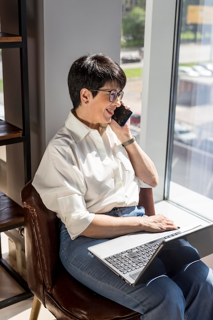 La empresaria sosteniendo su computadora portátil y hablando por teléfono