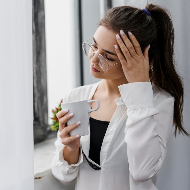 La empresaria sosteniendo una taza de café mientras trabaja desde casa