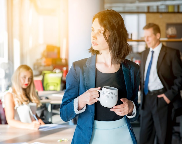 Foto gratuita empresaria sosteniendo la taza de café