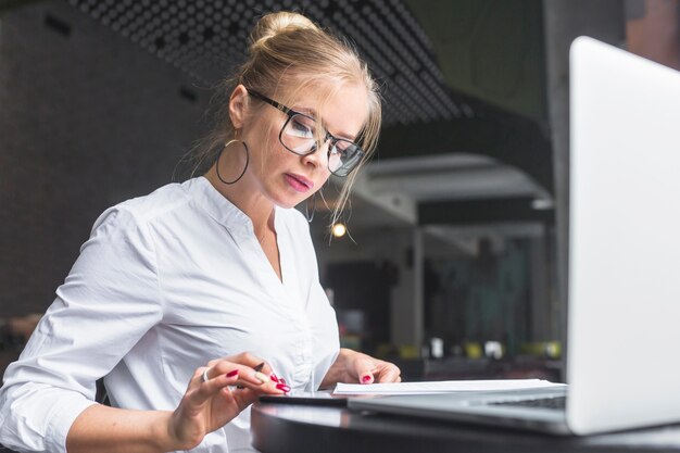 Empresaria con teléfono inteligente mientras toma notas