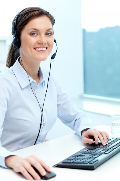 Empresaria trabajando en línea con un ordenador portátil y auriculares