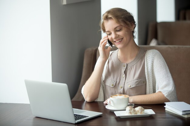 Empresaria usando su teléfono mientras toma un café