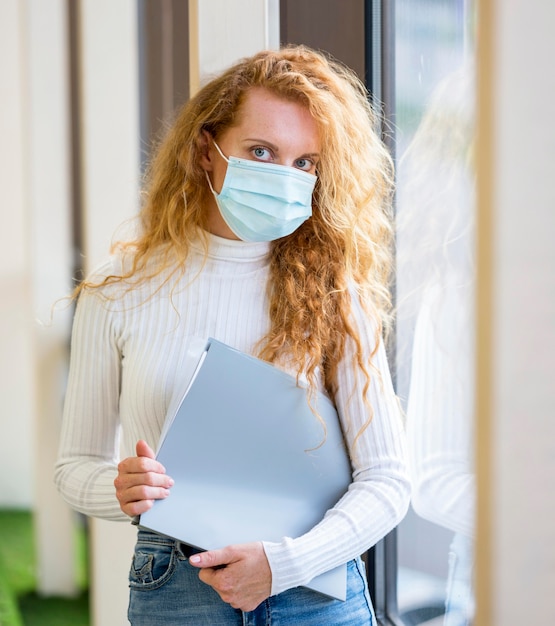 Foto gratuita la empresaria vistiendo máscara médica y sosteniendo documentos