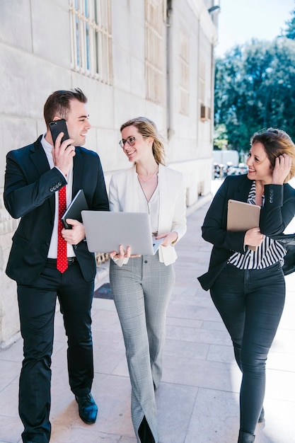 Empresarias alegres y empresario usando tecnologías