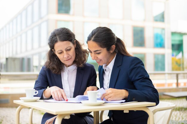 Empresarias que trabajan con documentos en café al aire libre