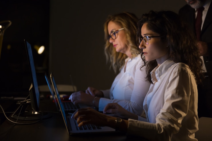 Foto gratuito empresarias serias que usan computadoras portátiles