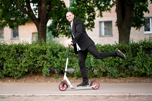 Empresario activo montando scooter al aire libre