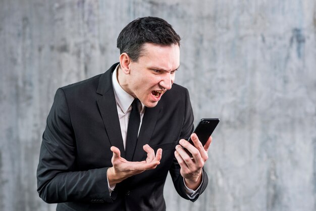 Empresario adulto enfadándose y gritando en el teléfono