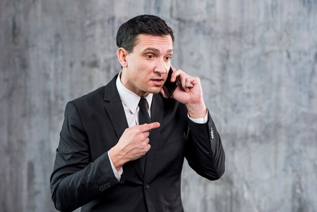 Empresario adulto irritado hablando por teléfono