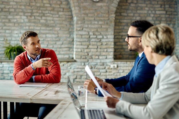 Empresario adulto medio comunicándose con el equipo de recursos humanos durante una entrevista de trabajo en la oficina