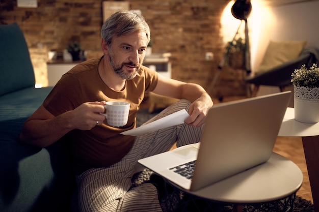 Empresario adulto medio en pijama trabajando tarde en la noche en casa