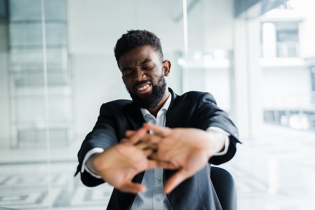 Empresario africano tomar un descanso durante la jornada laboral estirando las manos dedos comenzando el trabajo de oficina