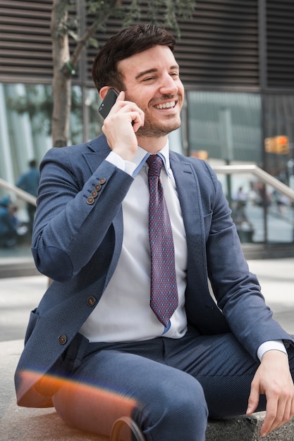 Foto gratuita empresario alegre hablando en teléfono inteligente