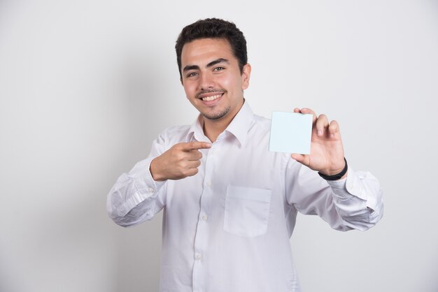 Empresario apuntando a blocs de notas sobre fondo blanco.