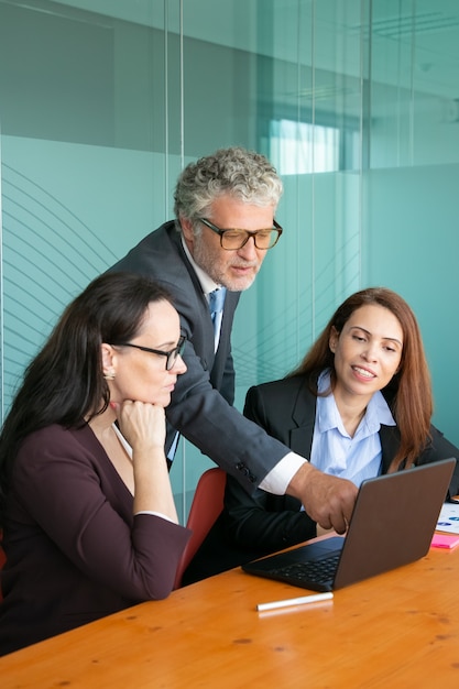 Empresario apuntando a la pantalla y mostrando los detalles del proyecto a un colega.