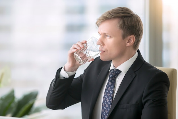 Empresario bebiendo agua en el escritorio