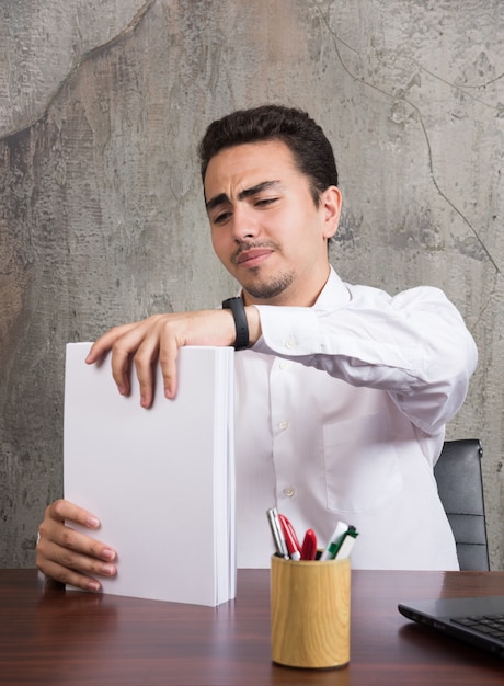 Foto gratuita empresario cansado con montón de papeles en el escritorio.