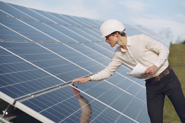 Empresario en un casco blanco cerca de batería solar