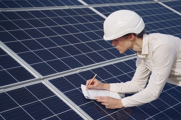 Empresario en un casco blanco cerca de batería solar