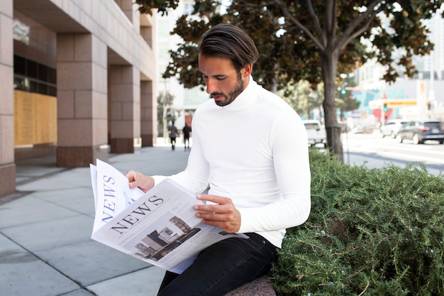 Empresario de cuello alto leyendo el periódico en la ciudad