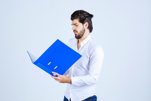 Un empresario dando poses con una carpeta de informes azul