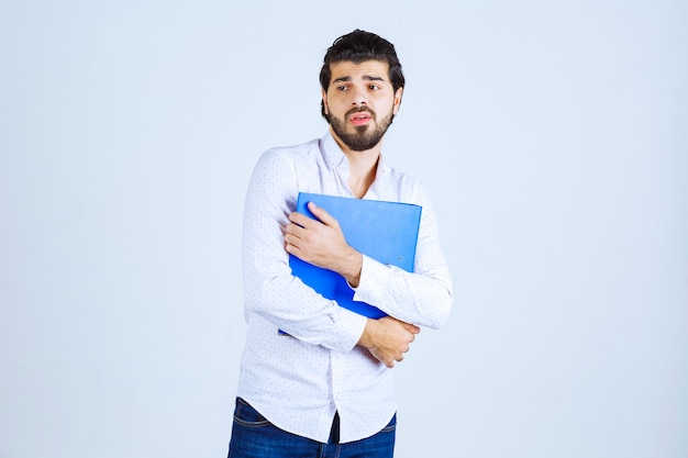 Un empresario dando poses con una carpeta de informes azul