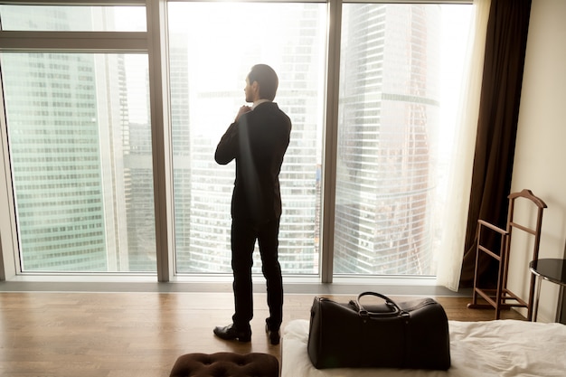 Empresario disfruta de vista desde la ventana en la habitación del hotel