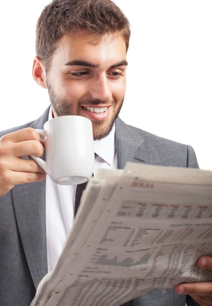 Empresario disfrutando su bebida caliente mientras lee las noticias